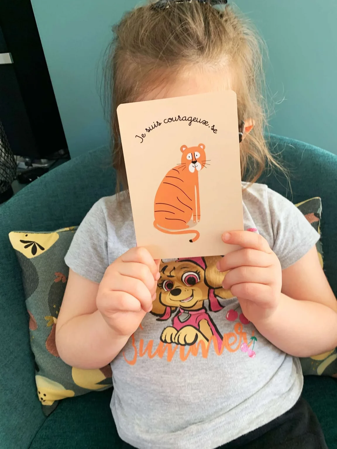 Photo d'une enfant tenant dans ses mains une carte Je d'amour.