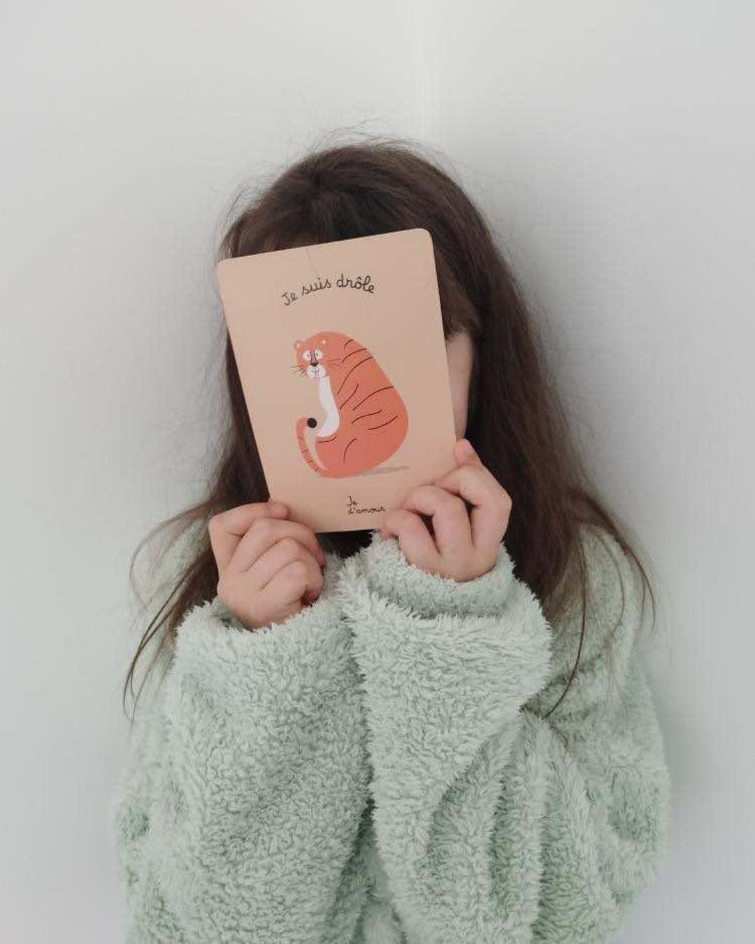 enfant qui prend confiance en elle avec la carte "je suis drôle" du jeu des affirmations positives
