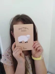 enfant qui tient une carte dans sa main "il y a toujours une solution à mon problème" issue du jeu des affirmations positives de Je d'amour qui permet de prendre confiance en soi